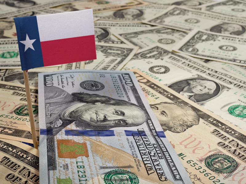 A variety of American bills with a Texas flag atop them